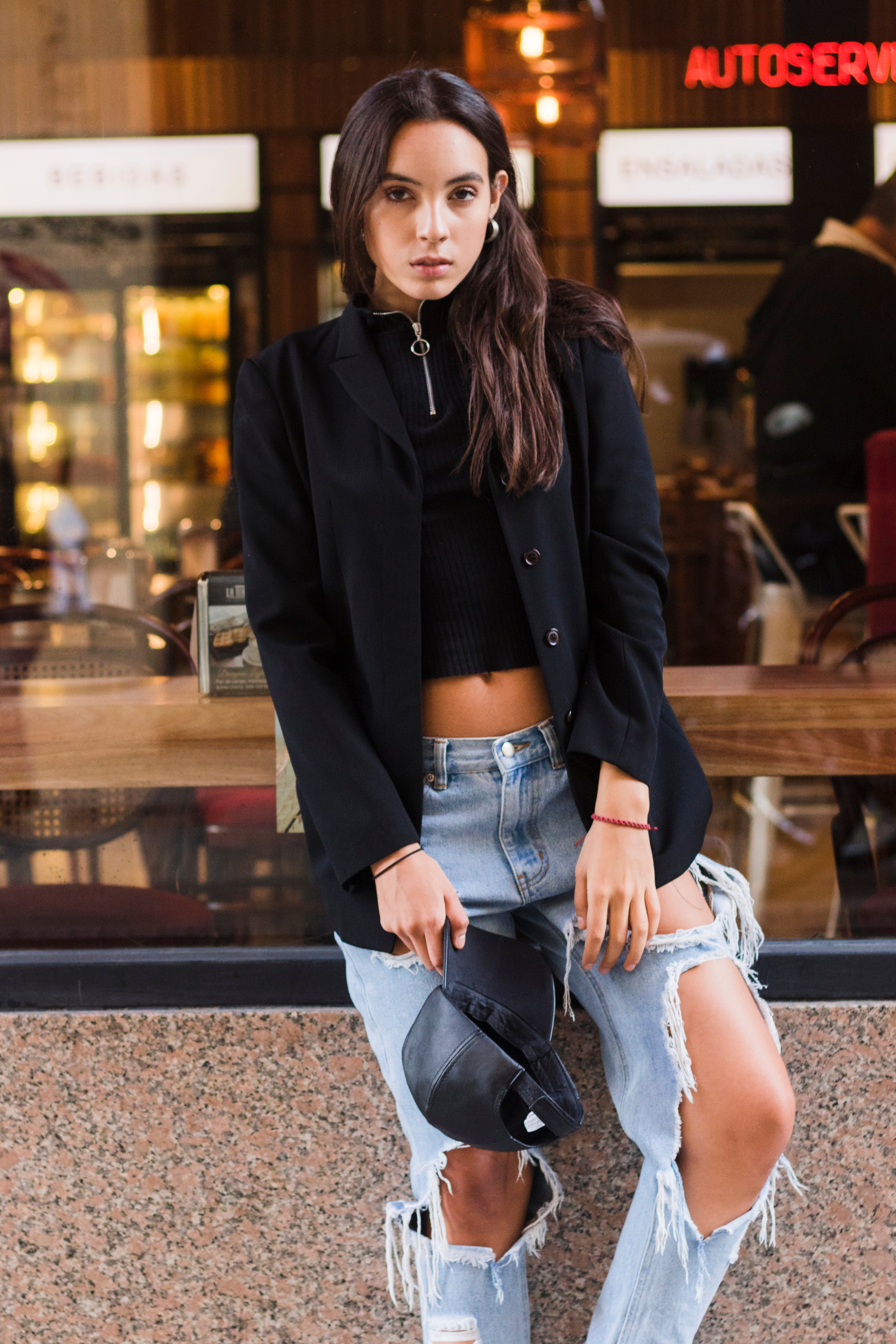 portrait-fashionable-young-woman-holding-cap-hand-standing-outside-restaurant.jpg